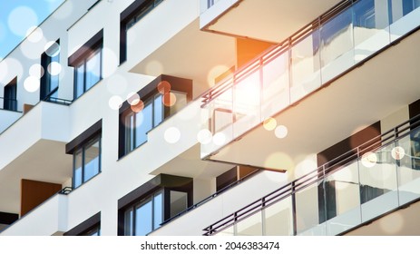 Modern apartment building on a sunny day. Architectural details and facade of a modern apartment building. Red sun on horizon, bokeh solar flare. 