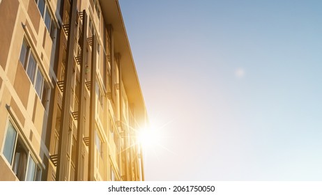 Modern apartment building on a sunny day. Architectural details and facade of a modern apartment building. Red sun on horizon