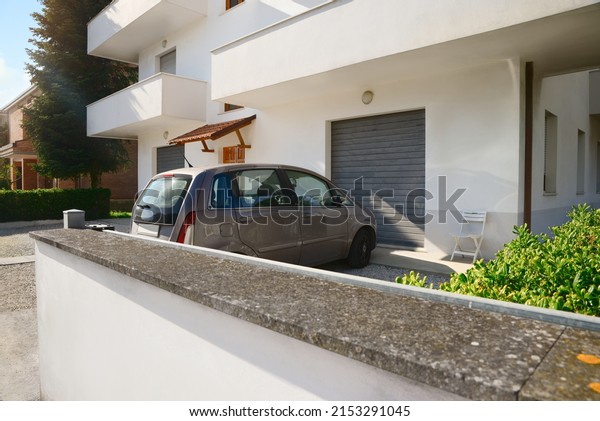 Modern apartment building with parked car in yard on\
sunny day