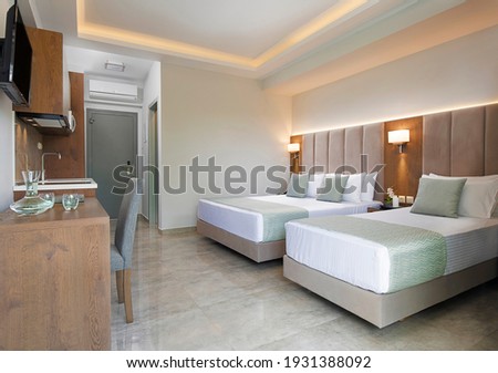 Modern apartment interior of bedroom with oak wood furniture, single, double king size bed, soft grey textile headboard. Contemporary family studio hotel room  with kitchen