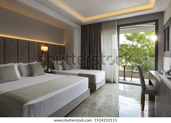 Modern\
apartment interior of family hotel room with grey oak wood\
furniture, single, double king size bed. Contemporary bedroom with\
open big window, green garden sunset view\
door
