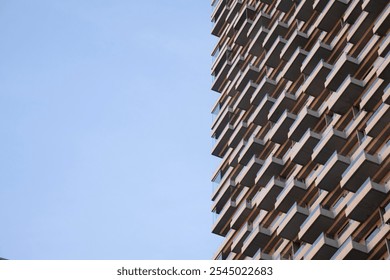 Modern architectural building facade with repetitive balcony patterns against blue sky. - Powered by Shutterstock