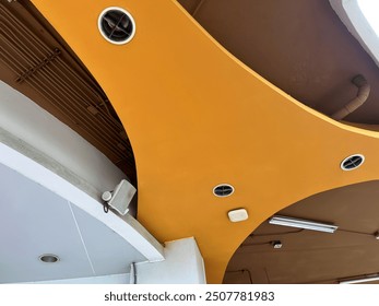 Modern architectural ceiling design with curved shapes and ventilation. warm orange color adds vibrant touch to space.  - Powered by Shutterstock