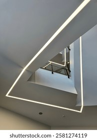 A modern architectural ceiling design featuring sharp geometric angles and sleek recessed lighting, creating a futuristic and minimalistic visual appeal.