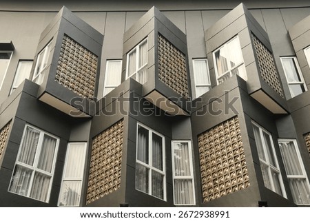 Modern architectural facade with geometric patterns, protruding windows, and elegant design. Contemporary building exterior showcasing urban style, symmetry, and creative construction details.