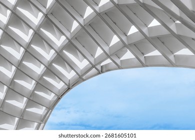 Modern architectural structure with geometric patterns and blue sky background.