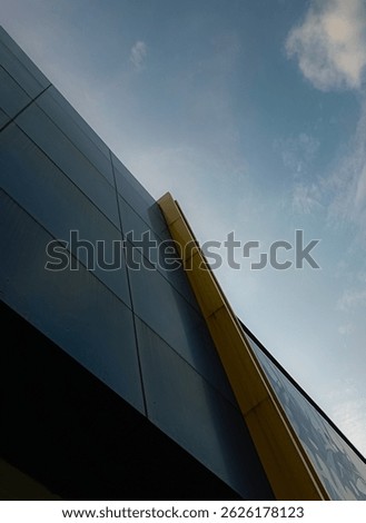 Modern architecture with dynamic angles and bold blue-yellow contrast under a clear sky. A minimalist and futuristic perspective of an urban building.
