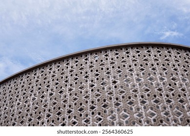 Modern architecture featuring a curved white facade with intricate geometric patterns against a clear blue sky. Contemporary design and aesthetics. Symmetry and innovative urban construction features. - Powered by Shutterstock - Get 15% off with code: PIKWIZARD15