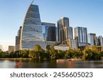 Modern architecture and high-rise buildings of Austin, Texas with summer sunlight reflections on Lady Bird Lake. A ground-level view of the lake and boats on the water.