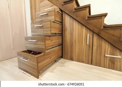 Modern architecture interior with  luxury hallway with glossy wooden stairs in modern storey house. Custom built pullout cabinets on glides in slots under stairs. Use of space for storage.