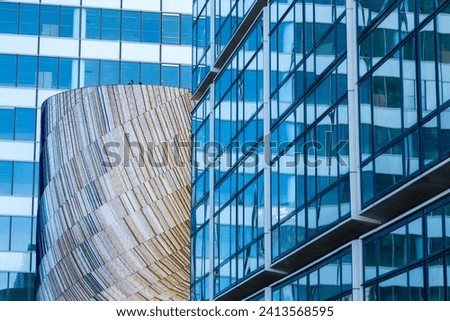 Modern architecture in La Défense, Paris, featuring a juxtaposition of glass facades with a curved wooden structure, reflecting the district's contemporary design ethos