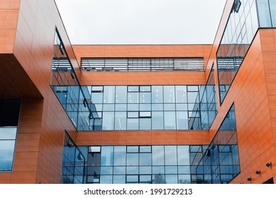 Modern architecture. Minimalist trendy urban office building, exterior. Orange wooden walls and blue glass windows outside during the day.