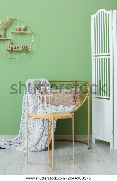 Modern armchair with table and folding screen near\
color wall