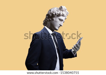Modern art collage. Concept portrait of a  businessman  holding mobile smartphone using app texting sms message. Gypsum head of of Apollo. Man in suit. 