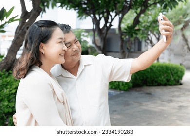 Modern Asian Senior Man taking selfie, capturing Precious Moments with His Wife Using a Smartphone - Powered by Shutterstock