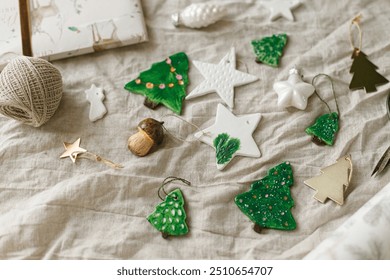 Modern authentic Christmas ornaments. Stylish handmade clay tree,star and mushrooms with scissors and thread on rustic table. Christmas gift decor. Winter handcraft and holiday preparation - Powered by Shutterstock