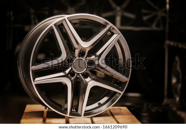 Modern automotive alloy\
wheel made of aluminum on a black background, industry. on a\
textured wooden table. Designer fashion wheels for car. Close-up,\
beautiful light.