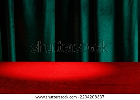 Modern background with empty red cloth table and green draped velvet curtains. Template for advertising, presentation, cosmetic products. Mockup, texture