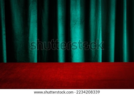 Modern background with empty red cloth table and green draped velvet curtains. Template for advertising, presentation, cosmetic products. Mockup, texture.