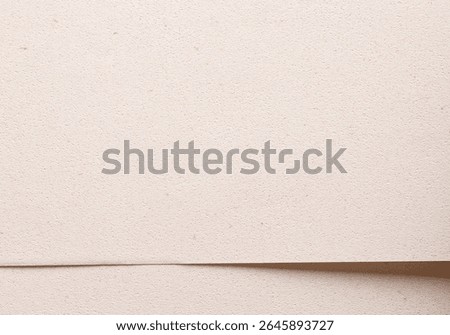Modern background with overlapping sheets of premium beige and cream paper. Soft grainy texture, organic fiber, and earthy speckled surface in minimal sustainable style. Closeup.