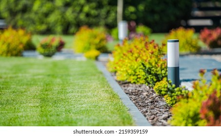 Modern Backyard Garden Decorative LED Lighting Along A Path And Lawn Area On The Other Side. Residential Landscaping Theme.