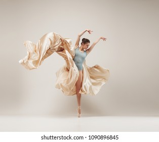 Modern ballet dancer exercising in full body on white studio background. Ballerina or female dancer with silk fabric dancing on white studio background. Caucasian model on pointe shoes