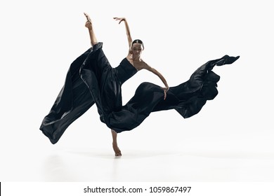 Modern ballet dancer exercising isolated in full body on white studio background. Ballerina or modern dancer in black silk dress dancing on white studio background. Caucasian model dancing barefoot
