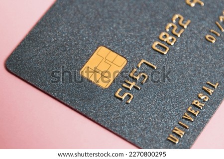 Modern bank card with chip macro on pink paper background