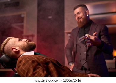 Modern Barber Male Begins To Cut Hair Of Client, Making Stylish Beard, Hair Cut In Salon