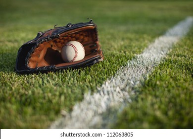 Modern baseball glove with ball in the grass near stripe in the field