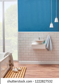 Modern Bath Room Sink Detail With Blue Wall And Ceramic Style. Decorative Mirror And Lamp In The Room And White Tub With Wooden We Floor. Slipper Towel Object In The Bath Room.