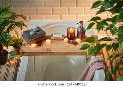 Modern Bath Room And Spa Center On The White Tub Wooden Table. Candle Soap And Towel Style With Vase Of Plant. White Marble Background Wall.