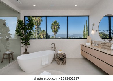 Modern bathroom with a freestanding tub, large window with a view of palm trees and mountains, and minimalist decor. - Powered by Shutterstock