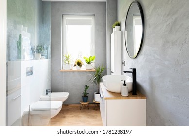 Modern bathroom with grey wall, white furniture and wooden tiles on a floor. Bright interior with window, mirror and stylish washbasin. Minimalism and scandinavian design of washroom.