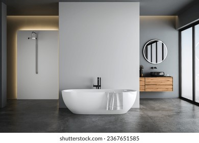 Modern bathroom interior with blue and white tones wall, concrete floor, wooden vanity with black sink and oval mirror, white bathtub, panoramic windows.