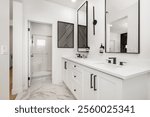 Modern bathroom interior with dual sinks, black fixtures, and geometric wall art, featuring white cabinetry and marble flooring.