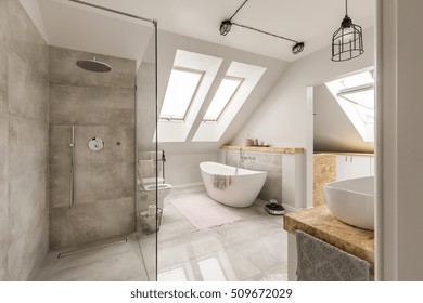 Modern bathroom interior with minimalistic shower and lighting, white toilet, sink, bathtub and roofwindows - Powered by Shutterstock