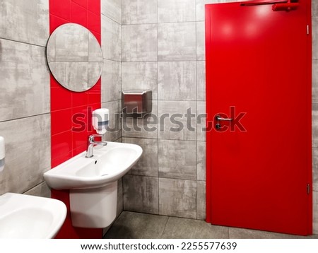 Modern bathroom interior with red accents. Red door and red tiles in the interior of the washroom.