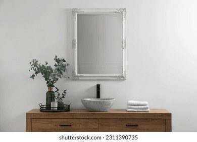 Modern bathroom interior with stylish mirror, eucalyptus branches, vessel sink and wooden vanity - Powered by Shutterstock