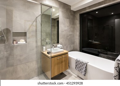 Modern Bathroom With A Shower And Bathtub Next To A Mirror And Tap With Washstand Illuminated At Night