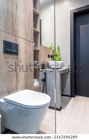 Modern bathroom with toilet, wash basin and wooden on the wall and floor. Minimalist interior of washroom with glass in new apartment. Vertical.