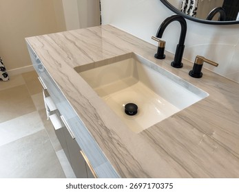 A modern bathroom vanity features a rectangular sink with a marble countertop. The design is clean, minimal, and stylish.