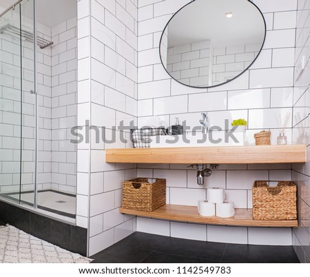 Modern bathroom with white tile and round mirror. Wide angle. Minimalist interior.
