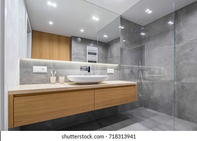 Modern bathroom with wooden countertop, shower, basin and big mirror