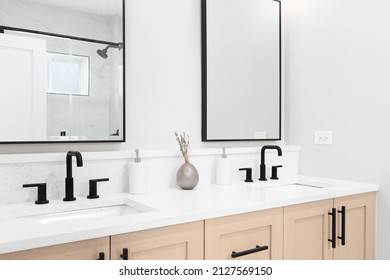 A modern bathroom with a wooden vanity cabinet, black faucets, white marble countertop, and black rimmed square mirrors. - Powered by Shutterstock