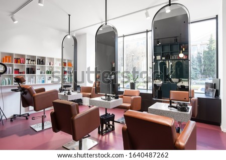 Modern beauty salon with places for makeup artist and hairdresser, big stylish mirrors, pink interior, no people