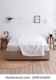 Moderno dormitorio decorado con muebles hechos a mano y suelos de madera. Cama doble con sábanas blancas elegantemente cubiertas sobre el colchón. Una parte del colchón es visible. Vista frontal. Conveniente para la maqueta