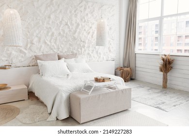 Modern Bedroom Interior Design Concept. Shot Of Large Light Minimalistic Room With Cozy Bed, White Walls And Big Window. Furniture And Domestic Comfort. No People