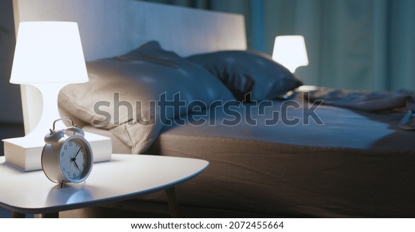 Modern bedroom interior at night time with design\
furnishing and alarm\
clock