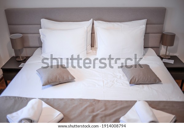 Modern bedroom with white bed. Bed maid-up with
clean white pillows and bed sheets in beauty bedroom. Close-up.
Interior background. Modern bedroom with  bed and set of white
color tone pillows